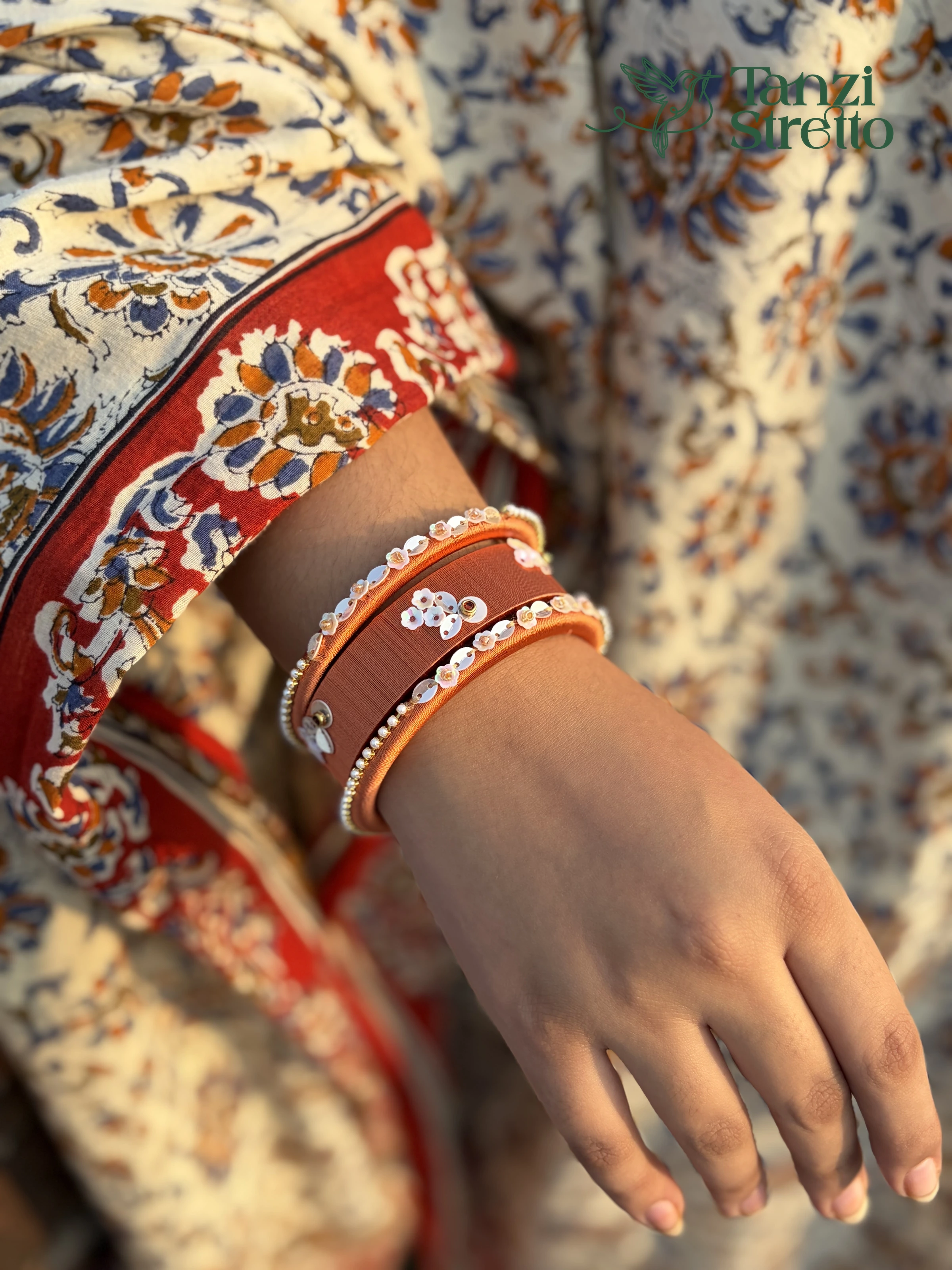 Rukmini bangles worn over a red and cream printed sleeve