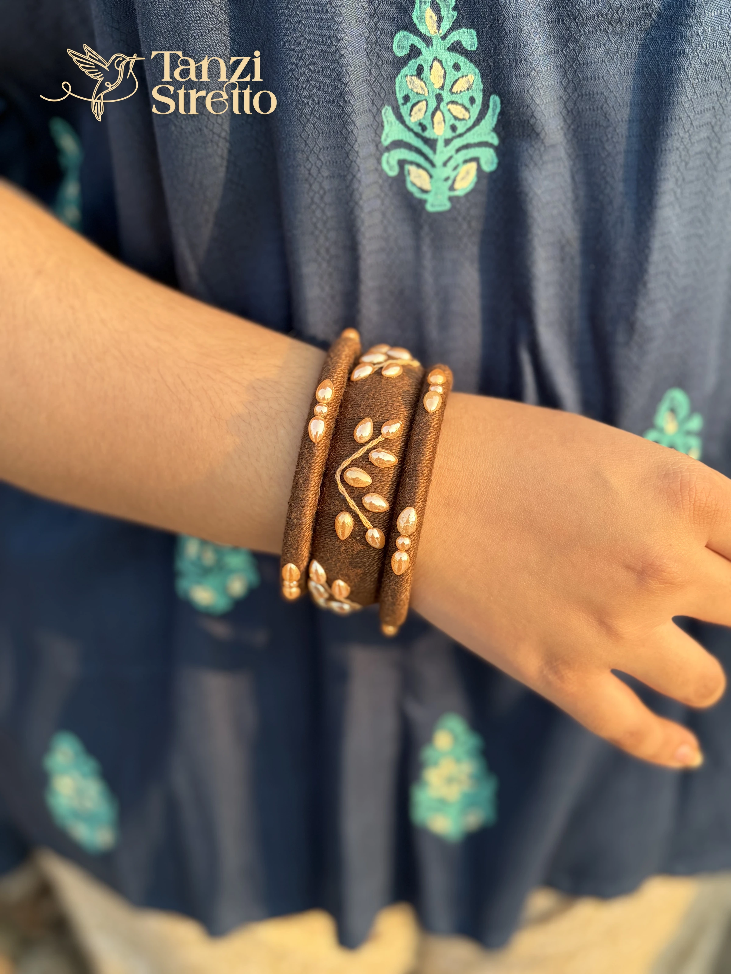 Nakshipata brown cotton thread bangles with a pearl leaf branch on a wrist