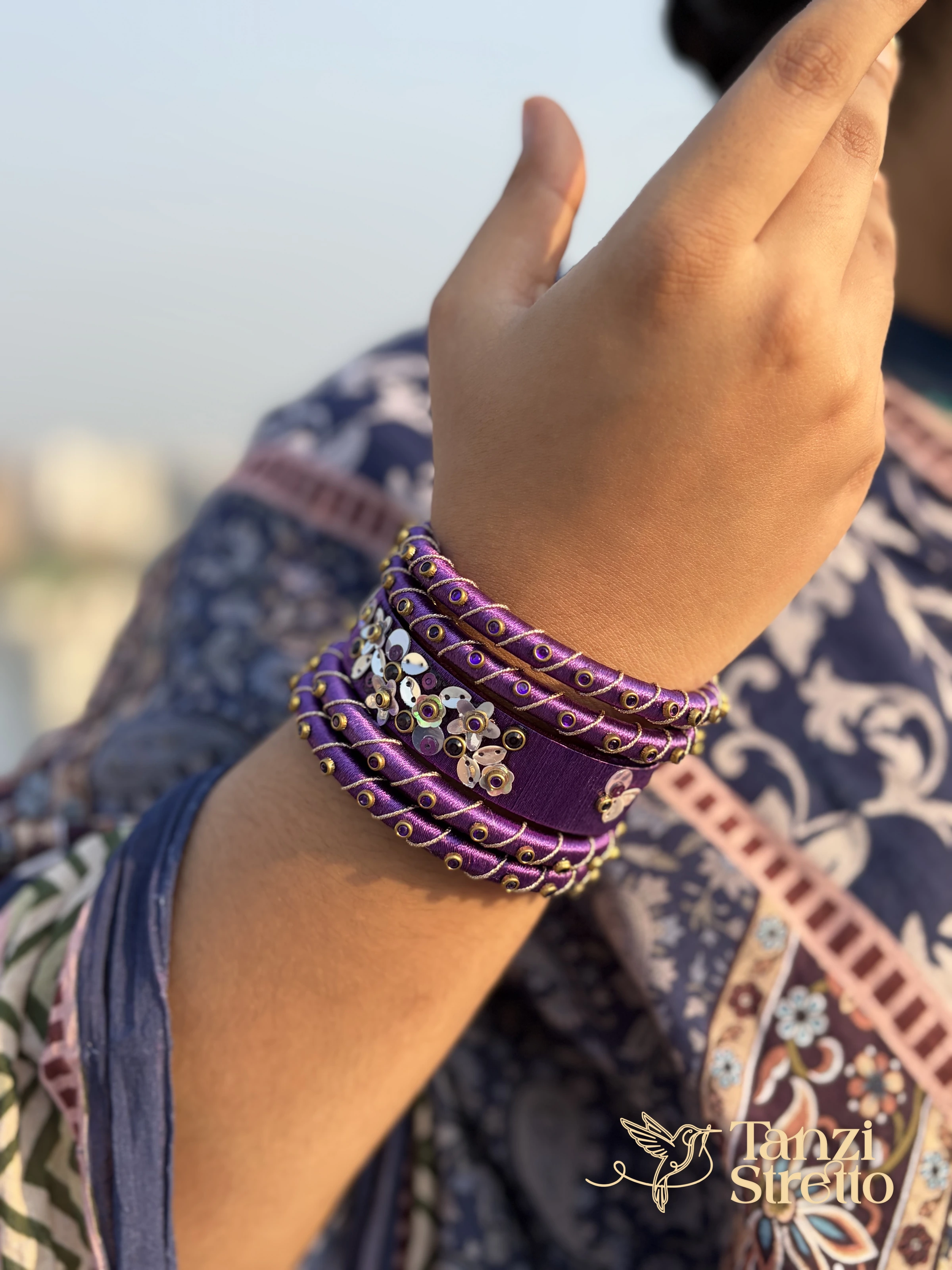Jarul violet bangle stack on a raised hand