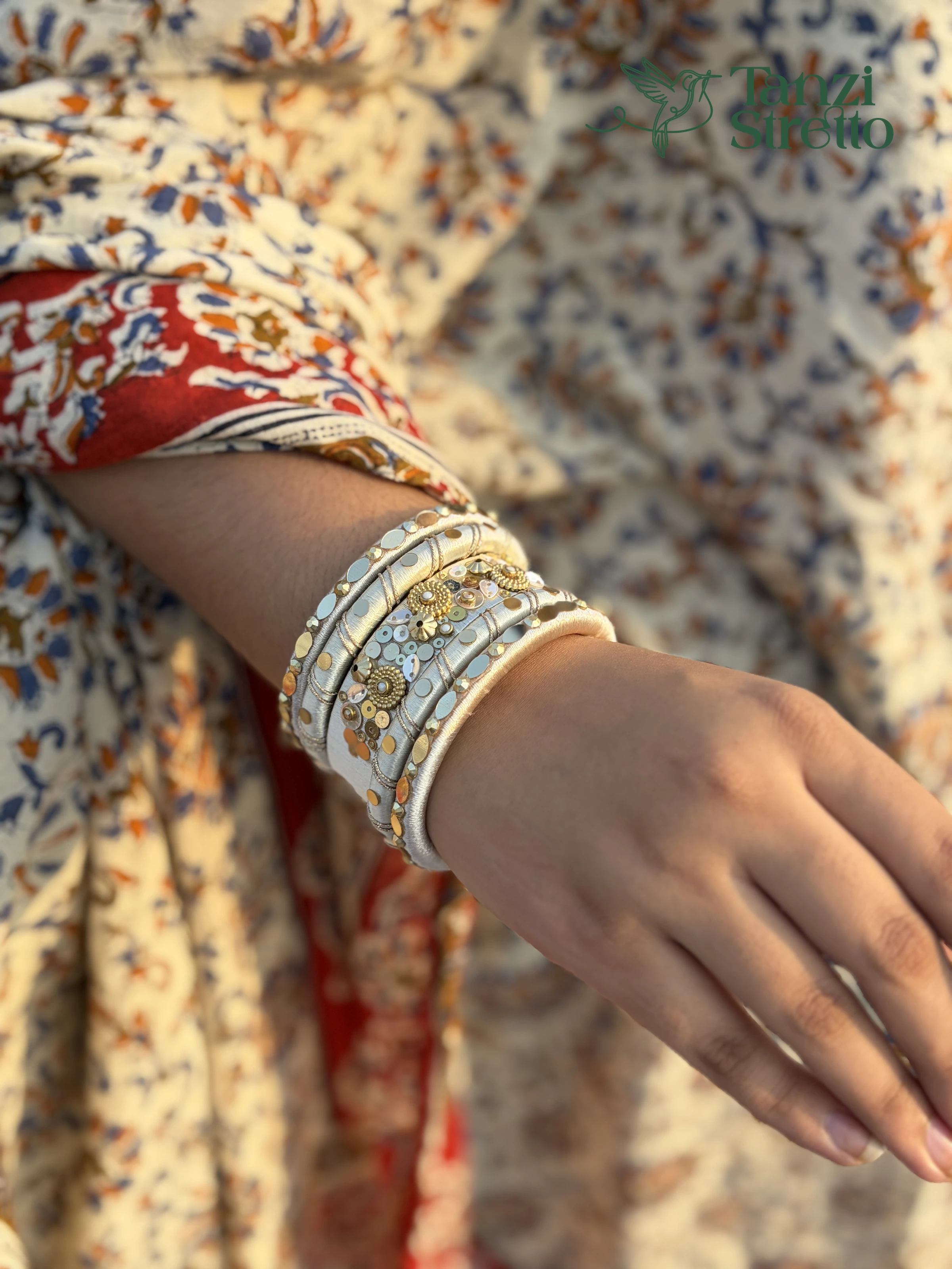 Pankouri 2.0 bangles worn over a cream and red printed sleeve