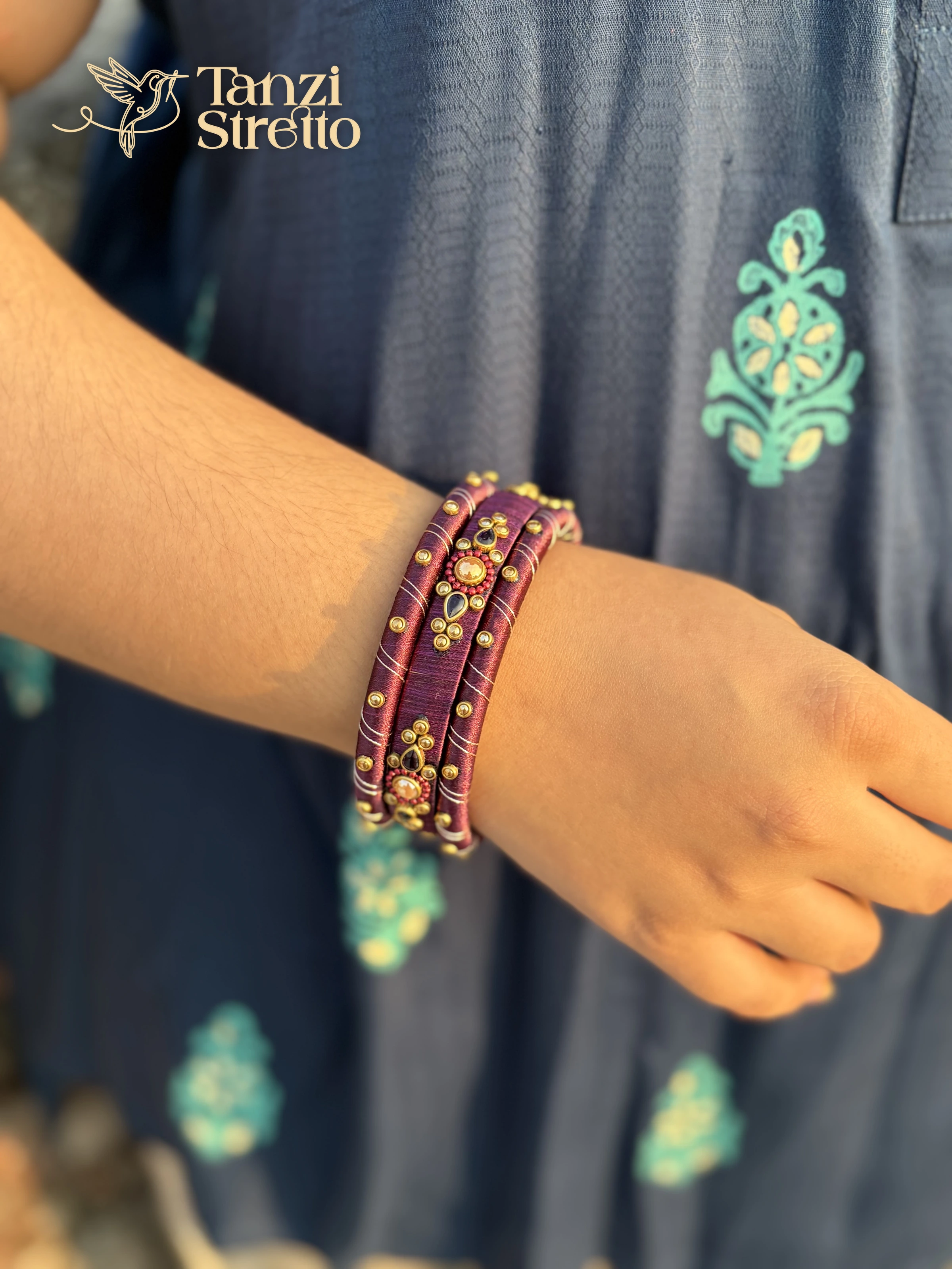Benarosi wine silk thread bangles with antique gold stones on a wrist