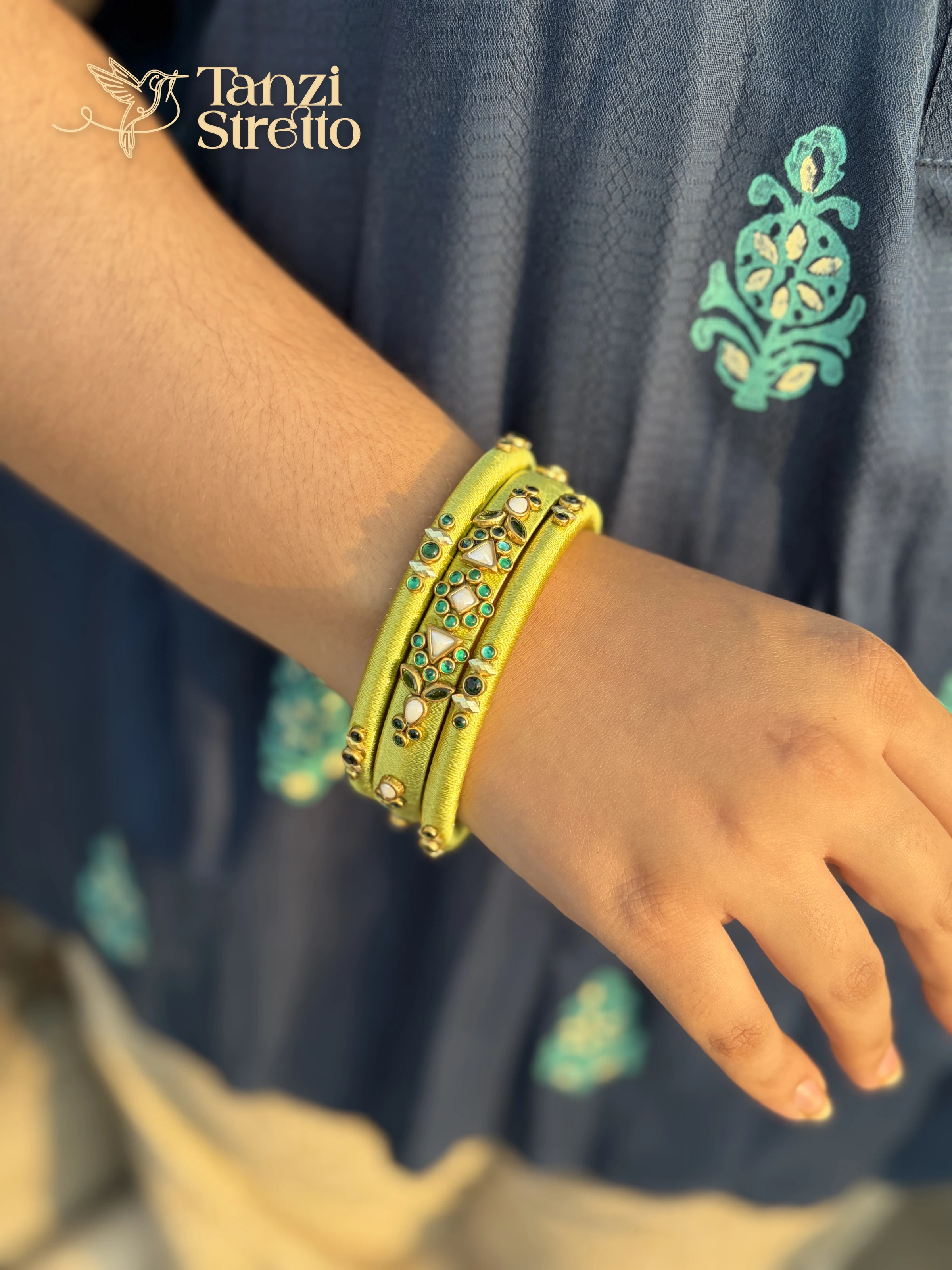 Moyurakkhi lime silk thread bangles with white and emerald stones on a wrist
